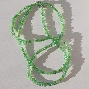 Halsband gjort med gröna glas och plast pärlor med klämma i metall.