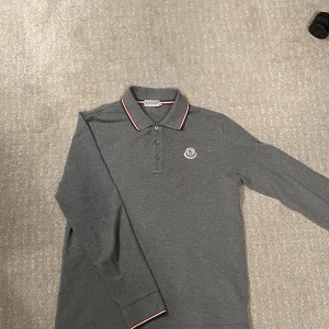 Moncler piké  - Säljer min långärmade moncler piké som är i väldigt bra skick! Den har inga hål eller fläckar. Skick 8,5/10. Storlek M. Självklart äkta. Hör gärna av dig om du har frågor! 