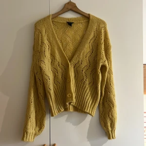 Gul cardigan - Gul stickad cardigan med mindre ballongärmar. Storlek L men passar även storlek XL.