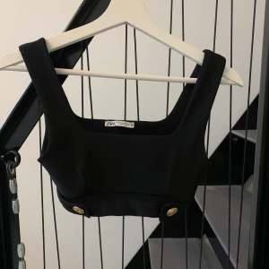 Topp från Zara - Topp med fina guldknappar som detaljer, perfekt till ett par höga jeans eller kostymbyxor. Storlek xs 