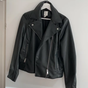 Snygg fakeskinnjacka från HM - Snygg jacka från Hm, endast använd en gång, superfint skick. Strl 42 men sitter snyggt oversized på mig som brukar ha 36/38. Pris exlusive frakt som köpare står för! 