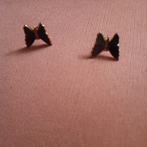 Guldfärgade örhängen Fjäril med grön emalj. - Fina guldfärgade örhängen med fjäril med grön emalj. Ej Guld .hämtas i Skene alt skickas o fraktfritt o Swishbetalning tillämpas .