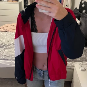 Vind/regnjacka - Säljer denna röd,blå,vit regn/vind jacka från Hollister i storlek L men skulle säga att den mer är som S/M. Ganska andvänd men har ändå hållit sin kvalite bra och är väldigt fin