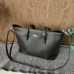 En svart ganska basic handväska, bra skick👍🏻 Axelband och vanliga ”handtag”, 3 fickor invändigt och en på baksida. 