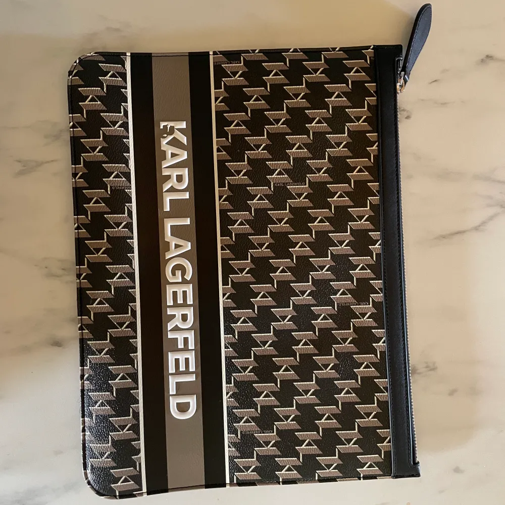 En KARL LAGERFELD cloutch i ny skick. Den 31x22 cm. Köptes för skulle användas som data fodral, men kommer inte till användning. Passar MacBook Air. Påse till väskan finns. . Väskor.