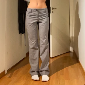 Gråa lågmidjade kostymbyxor - Jättefina lågmidjade kostymbyxor i storlek 4 från banana republic, säljer pga de tyvärr är för stora i midjan, köpta secondhand ❣️(håller i byxorna där bak i första bilden) Innerbenslängden är 80cm