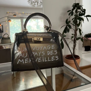 Handväska - UN VOYAGE AU PAYS DES MERVEILLES Jelly Bag Tote Handbag i grå/svart färg. Använd fåtal gånger och i fint skick.