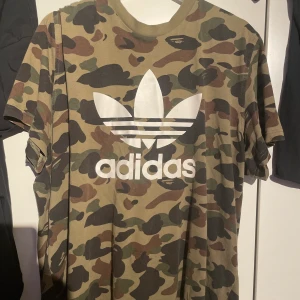 Bape x Adidas T-shirt - Bape och Adidas tröja släpptes 2018 Finns på vissa hemsidor som tex Goat.com där tröjan säljs för 250-350 Dollar