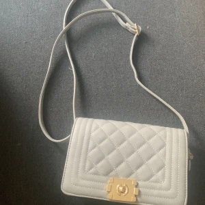 Grå väska - En liten väska som är lätt att gå runt och bära på,man kan korta till den om man vill elr göra den längre o den har ett litet fack i sig