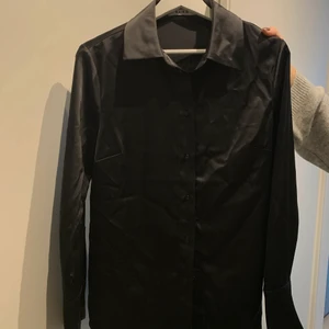 Skjorta i silkesmaterial  - Svart oversized skjorta i silke från Na-kd. Använd ca 1-2 ggr så precis som ny. Storlek 36 men passar även 34 & 38 beroende på hur man vill att den ska sitta.
