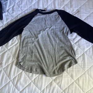 Grå och svart tröja - Det är en grå tröja med svarta armar och krage, storlek XL