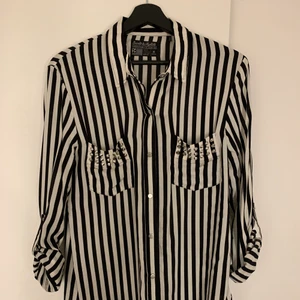 Svartvit randig skjorta med nitar - Randig skjorta köpt från Carlings sen många år tillbaka. Snygg med svartvita ränder och nitar på båda bröstfickor. Bölden som håller/knäpper upp ärmarna om de rullas upp. Använd några gånger men fint skick