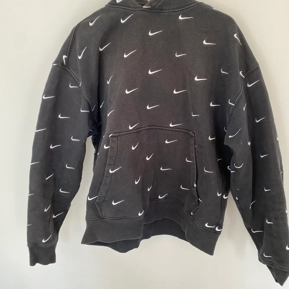 Svart Nike hoodie med Swoosh-detaljer! Köptes i London på ’Size?’. Den är till viss del cropped men lite bredare/oversized. Väldigt mysig! Storleken är XL men jag skulle säga att det är en L eller översized M! Använd rätt så mycket men inga skador någonsin.. Hoodies.