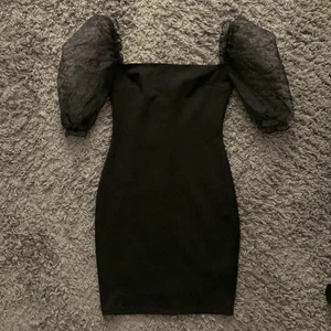 Svart klänning med puffärmar - Svart figurnära klänning med puffärmar från NELLY, använd endast en gång så den är sparsamt använd