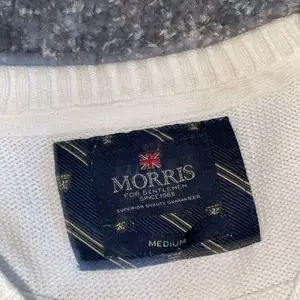 Den är vit stickad lite knottrig (bara på Morris bokstäverna).     Frakten står köparen för!!!!!