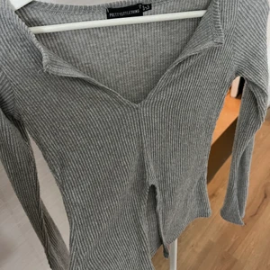 Grå långärmad topp - Köpt på PRETTYLITTLETHING. Använd fåtal gånger. Kan skicka bild med den på :) Slits på armarna.