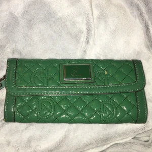 Grön väska guess - En kuvertväska i trendig, grön färg. Från guess. Går att sätta fast en axelrem ifall man vill. Väskan är äkta. 