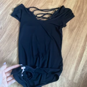 Svart boddy med öppen rygg - Kortärmad boddy(string) med öppen rygg.