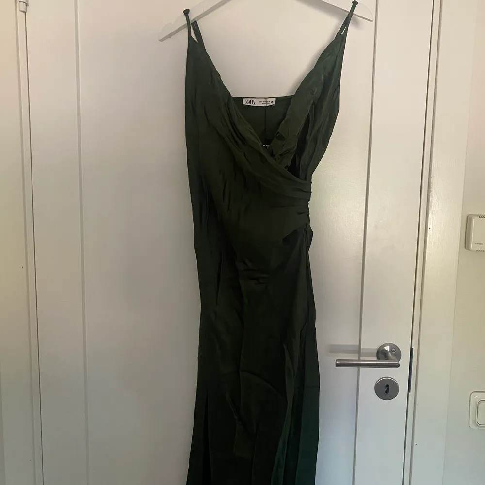 En mörkgrön satinklänning som man kan klä upp och ner. Har den redan i brun och är lätt att bära på olika tillfällen. Denna är aldrig använd. Ny pris 399 Säljer för 150:- . Klänningar.