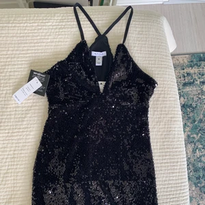 Svart paljettklänning  - En svart paljettklänning/festklänning med prislapp på. Aldrig använd. Från Nelly i storlek M men passar även S. Stretchig kort klänning med urringning. Frakt tillkommer!