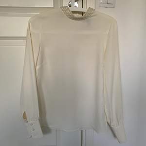 En vit blus från H&M som passar Xs/S med pärlor i kragen. Är i gott skick. Frakt tillkommer!