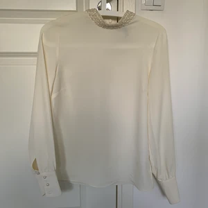 Vit blus med pärlor i kragen - En vit blus från H&M som passar Xs/S med pärlor i kragen. Är i gott skick. Frakt tillkommer!