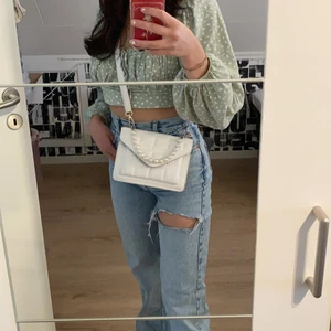 Vit väska med pärlhandtag och rem. - Säljer nu min super fina vita väska då jag har så många och behöver prioritera bort några. Använd ett fåtal gånger så inga repor eller märken! Inga fack inuti förutom ett litet på utsidan. Längd: 20cm, Höjd: 14cm, Djup: 7cm, Handtagshöjd: 10cm, Remlängd: 110cm. Bandet är justerbart. 109kr och gratis frakt 🤗 Vid frågor, skriv till mig! 