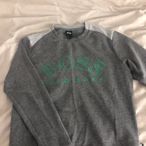 Hugo Boss tröja - Hugo boss tröja i nytt skick. Mörkare grå med ljusgrått på axlarna och grönt tryck.