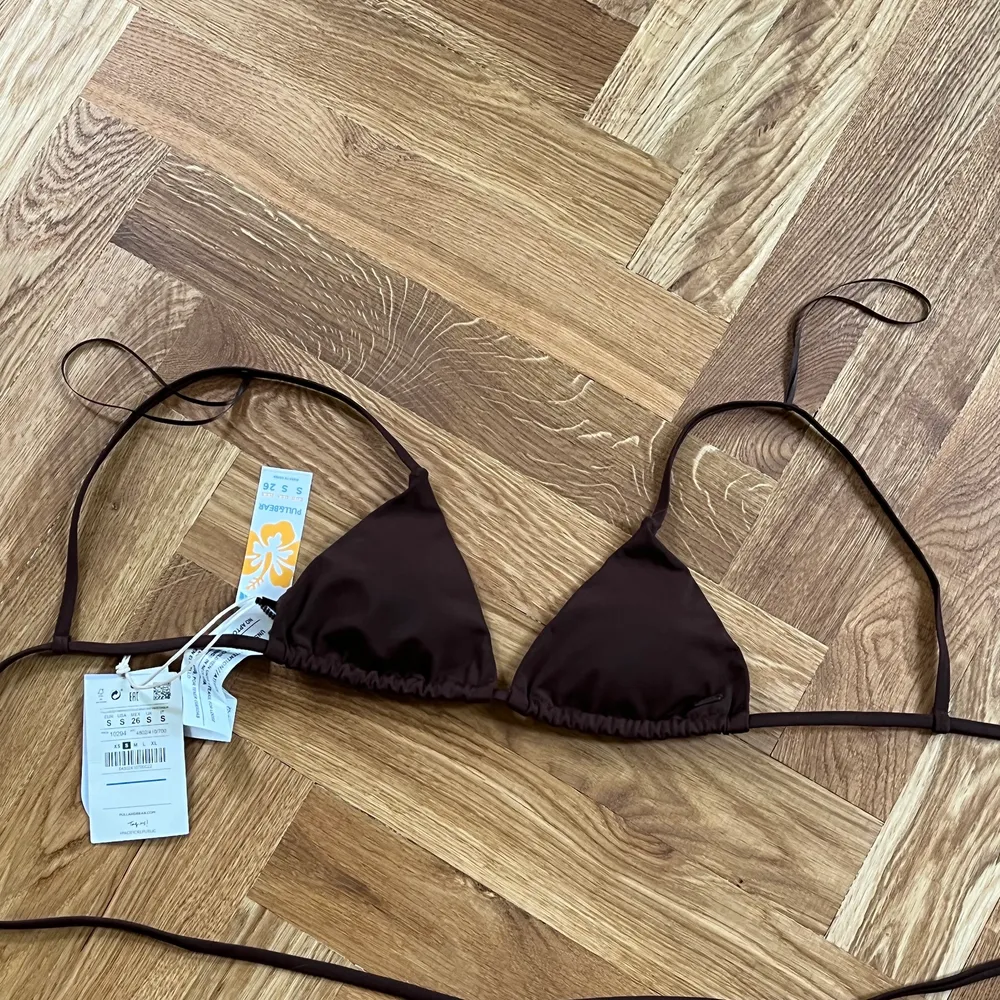 Brun bikinitopp från pullandbear, såå snygg när man är brun och har snygga detaljer som extra band runt magen, gör att man får lite mer figur. Endast provad. Jag är en S men skulle säga att den passar en XS också eftersom bysten är ganska liten.. Toppar.