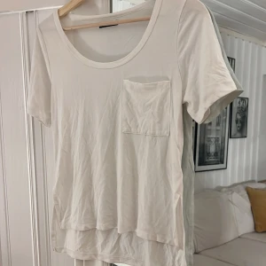 T-shirt  - Vit T-shirt med ficka i storlek xxs, men passar mig som pendlar mellan xs och s. Frakt tillkommer 