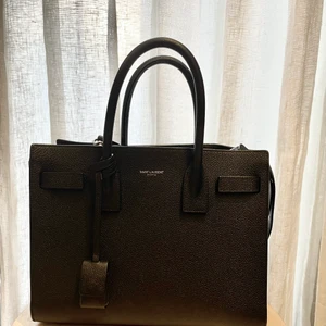 Saint laurent Sac de jour  - Säljer min älskade saint Laurent Sac de jour i baby storleken. Perfekta väskan som funkar till alla tillfällen. Kan bäras crossover, i armvecket eller på axeln med ett strap som tillkommer. Världens bästa kvalité så den är som i nyskick! Möts endast upp i stockholm och betalning sker via swish.  Nypris 21.000:-  Pris kan diskuteras vid snabb smidig affär. 