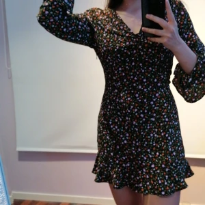 Sommar-klänning - Aldrig använd, sommar-klänning, svart med blommig mönster och perfekt till en sommarkväll! Klänningen har en dragkedja på sidan och är lite för stor för mig v-neck (jag har använt säkerhetsnål), den är i storlek M.