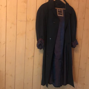 Trenchcoat vintage - Snyggaste trenchcoaten i navyblå med lila innerfoder. Den e i toppskick. Går någon cm över knäna på mig som är 170. Passar allt från xsmall till medium skulle jag säga
