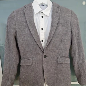 Barnkavaj med skjorta - Kavaj med skjorta stl 140 I fint skick, använd fåtal gånger Kavaj grå från H&M skjorta vit med svarta knappar från Cubus