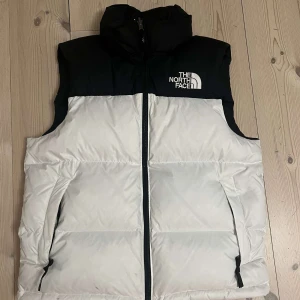 The North Face väst - Vit och svart väst från The North Face. Använd endast ett fåtal gånger. Köpte den för cirka 3000.