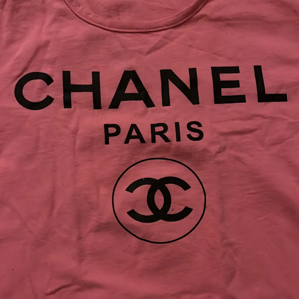 En rosa baby tee med Chanel tryck, står ingen storlek men skulle säga att den passar en S. T-shirts.