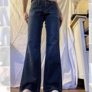 Skitsnygga lågmidjade vida/bootcut jeans. Så fina fickor både fram och bak! Säljer då de är lite för små😭 Modellen på bilden är ca 173cm lång, midjemåttet är 42cm och innerbenslängden är 82cm. Hör av dig vid frågor eller intresse!🥰💕