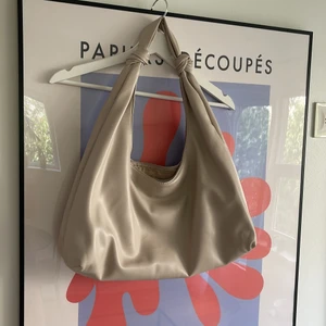 Beige väska  - Stor tote bag med innerfack. Väskan är beige och har en axelrem med knytdetaljer. Väskan är använd Max 1 gång och köptes för 399kr på Zalando. 