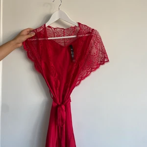 Röd morgonrock med spets - Sexig röd morgonrock i ”satin” material. Med spets detaljer och knytning i midjan. 