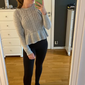 Stickad tröja  - Ljusgrå stickad tröja med volang från Nelly. Storlek S men passar även som XS.