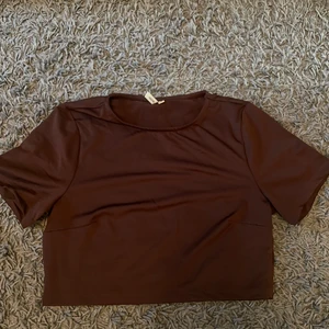 Brun croptop  - En brun croptop i ett elastiskt, polyester material från Nelly. Aldrig använd. Storlek M. 50 kr + 29 kr frakt 