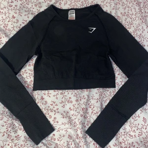Crop Top Gymshark - Säljer superfin croptop från Gymshark. Mörkgrå i storlek L. Använd få gånger och inga fläckar eller slitningar. Hål för tummarna i armarna och logga fram+bak. Frakt 15 kr💖  Ord. Pris 449 kr