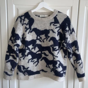 Stickad tröja från Carin Wester - Ljusgrå stickad tröja från Carin Wester med mörkblå hästar. Jättefint skick. 