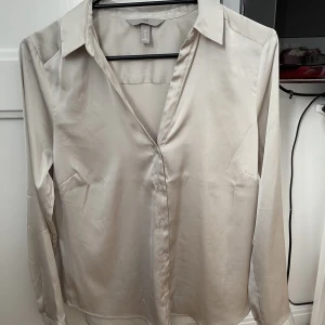 Siden blus/skjorta - Säljer en siden blus/skjorta i en beige färg. Super fin, aldrig använd då jag tycker att färgen inte passar på mig! Bra skick!