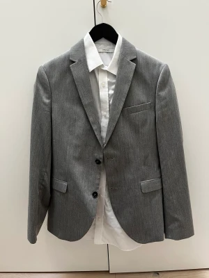 Kostym Jack & Jones  - Kostym från skolavslutning som bara hängt i garderoben.  Innehåller kostymbyxor och vit skjorta och kostymfodral också  Orkar du inte köpa en ny kostym bara för ett tillfälle, då har du din chans här! 