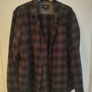 Svart grå flanellskjorta - Den är svart och grårutig,ser ut att vara typ orangeaktig på bilderna men det är bara min kamera som sugereeer