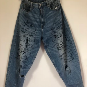 Jeans med klotter - Blåa jeans med klotter, rivna och trasiga med mening.  