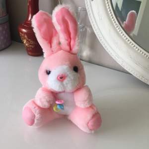 Rosa sött kanin  gossedjur . Den tvättbar ,maskin tvätt går jätte bra. Den har halsband med tre plast hjärtat i tre färger .storlek på kanin är ca21cm