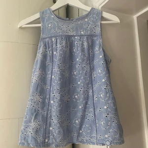 Söt Superdry blus - Otroligt söt och blå blus med vita blommor. Öppning med knappar i ryggen och fina detaljer, spets vid ringningen samt hålsömnad både på fram och baksida. Använd, men i bra skick. Bandet till fösta och sista knappen är slitet (bild 3). Frakt tillkommer!  