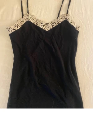 Intimissimi linne - Snygg svart linne med tunna axelband och dekorativ beige/vit spets längs urringningen. Kan gå ner i pris!